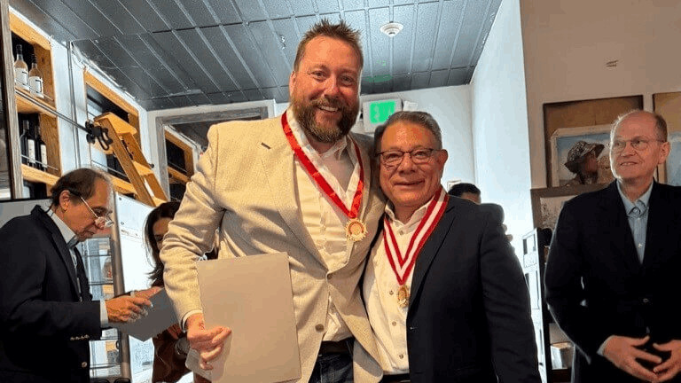 John Billimek and Cesar Aranguri stand together with medals around their necks. Aponte and Casafrancas are in the background.