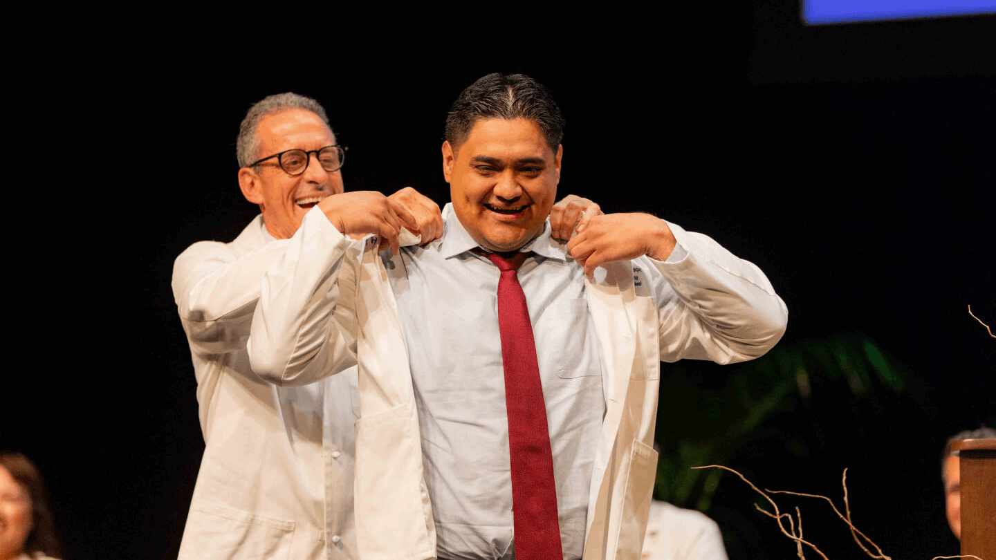 Dr. Stamos putting on a students white coat